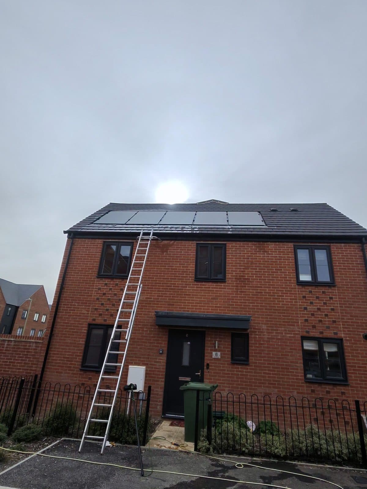 A ladder up to the first floor of a red-brick house, mid-job.