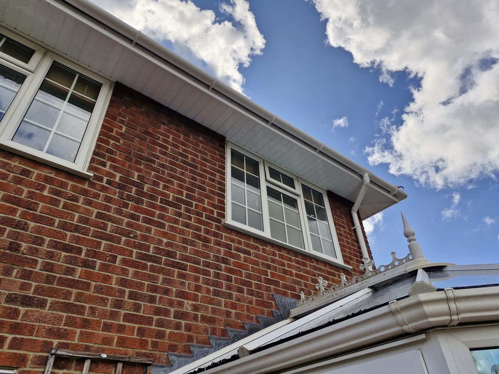 A red-brick house with white fascias and the edge of a conservatory roof.