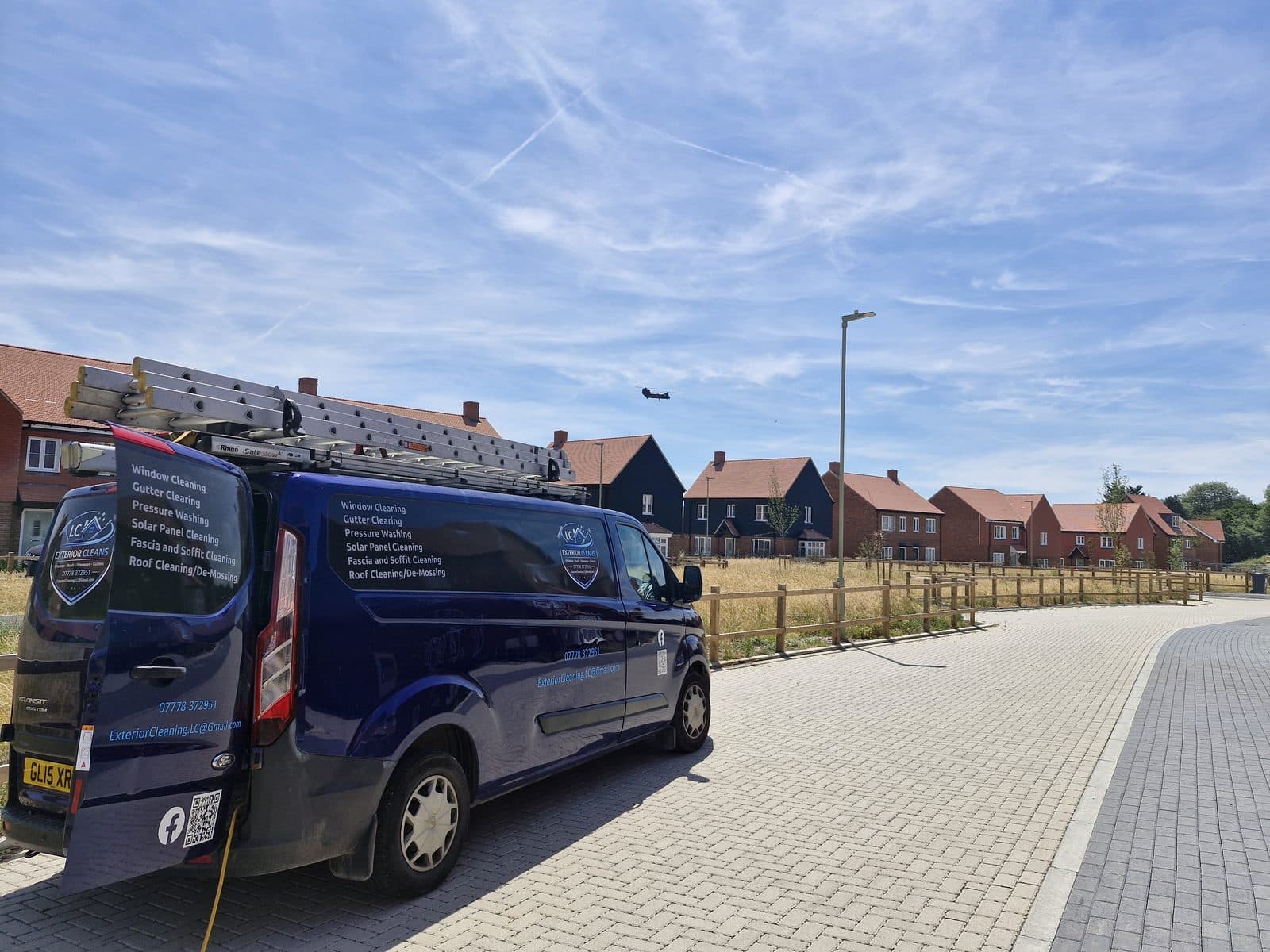 The LC Exterior Cleans van with ladders on the roof, parked on a new-build street.